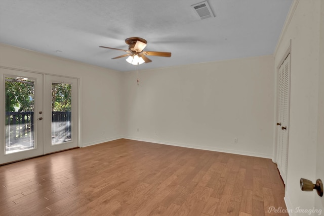 empty room featuring light wood-type flooring, ceiling fan, crown molding, and french doors