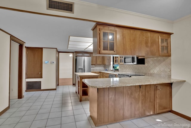 kitchen with appliances with stainless steel finishes, kitchen peninsula, light tile patterned floors, and decorative backsplash