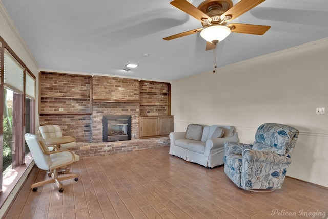 living room featuring brick wall, ceiling fan, light hardwood / wood-style flooring, and a brick fireplace