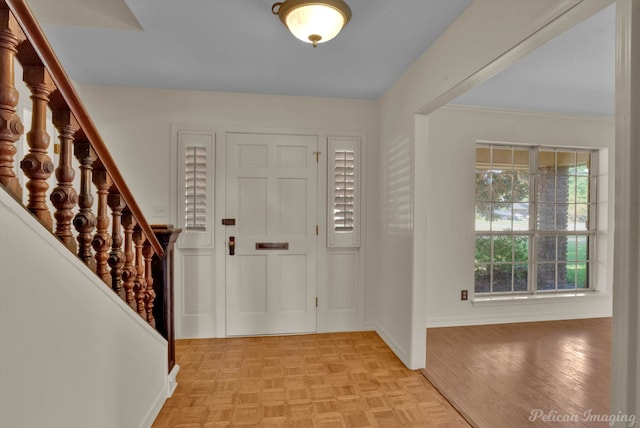 foyer entrance with crown molding and light parquet floors