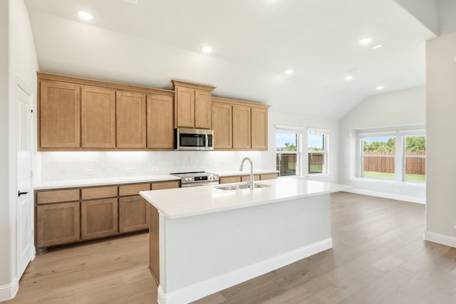 kitchen featuring vaulted ceiling, appliances with stainless steel finishes, sink, and an island with sink