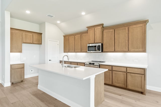 kitchen with sink, appliances with stainless steel finishes, light hardwood / wood-style flooring, and an island with sink