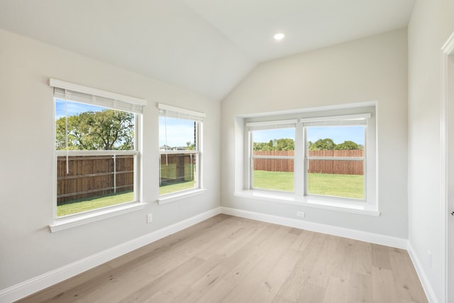 spare room featuring light hardwood / wood-style floors and lofted ceiling