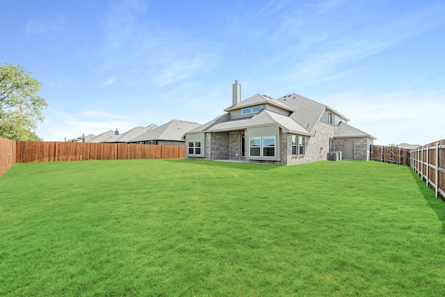 rear view of house featuring central AC and a yard