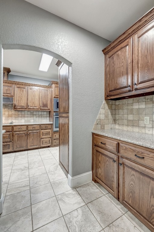 kitchen with decorative backsplash, oven, and light tile patterned floors