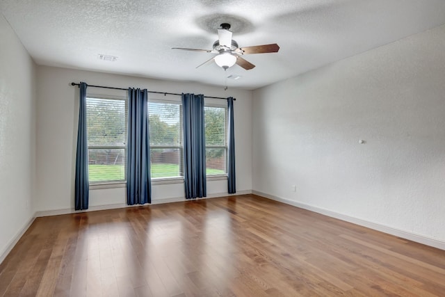 empty room featuring plenty of natural light, ceiling fan, and hardwood / wood-style flooring