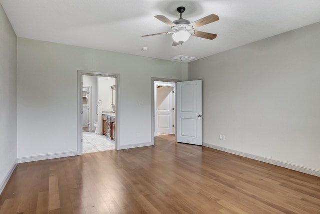 unfurnished bedroom with ensuite bathroom, light tile patterned floors, and ceiling fan