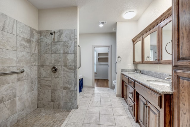 bathroom with dual vanity, a tile shower, hardwood / wood-style flooring, and toilet