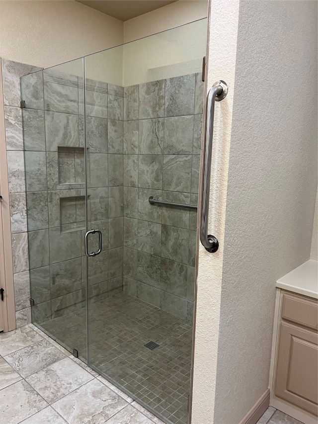 bathroom with a shower with shower door, vanity, and tile patterned flooring