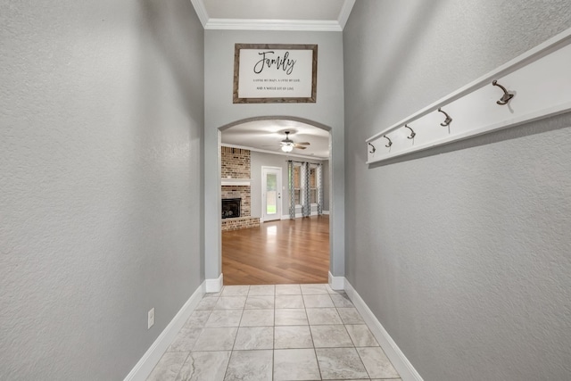 hallway with light tile patterned flooring, brick wall, and crown molding