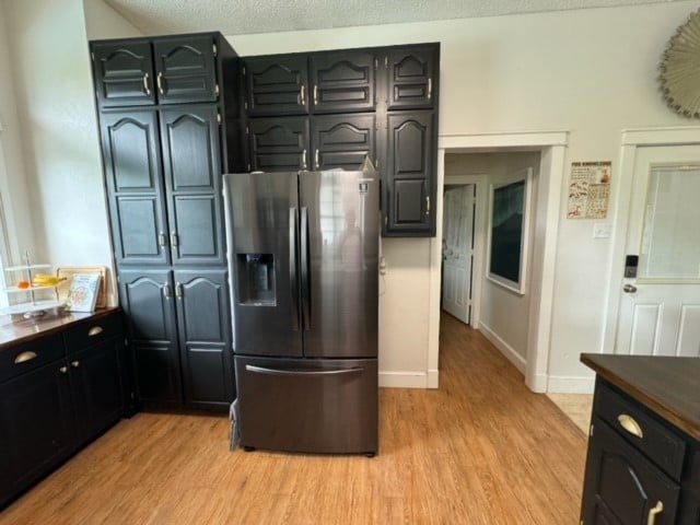 kitchen featuring a textured ceiling, light wood-type flooring, and stainless steel fridge