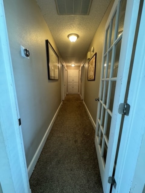 corridor with carpet flooring and a textured ceiling