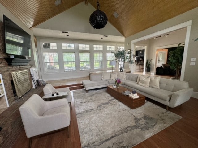 living room featuring wood ceiling, dark wood-type flooring, a brick fireplace, and high vaulted ceiling