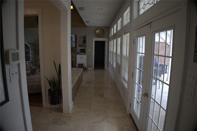 corridor with french doors, light tile flooring, and built in shelves