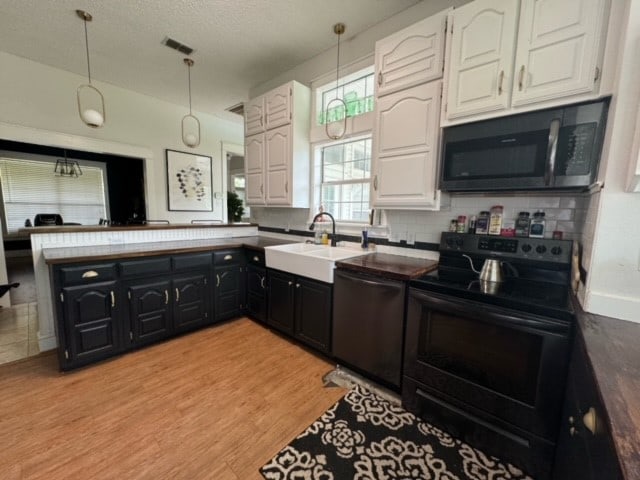 kitchen featuring decorative light fixtures, light hardwood / wood-style flooring, black appliances, white cabinetry, and sink