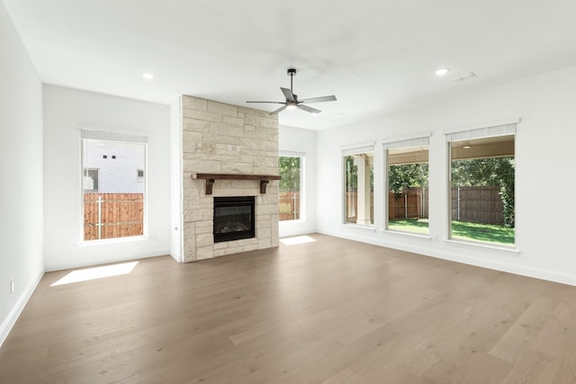 unfurnished living room featuring a stone fireplace, ceiling fan, and light hardwood / wood-style flooring