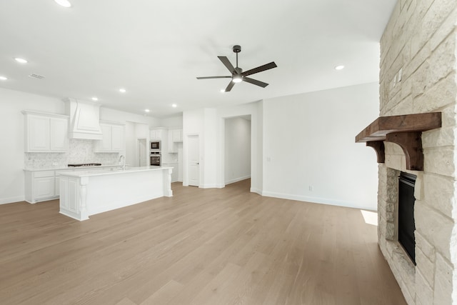 kitchen featuring a kitchen island with sink, light hardwood / wood-style flooring, stainless steel appliances, and white cabinetry