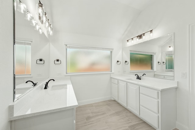 bathroom featuring lofted ceiling, vanity, and a wealth of natural light