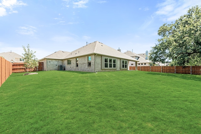 back of property with a yard and central AC