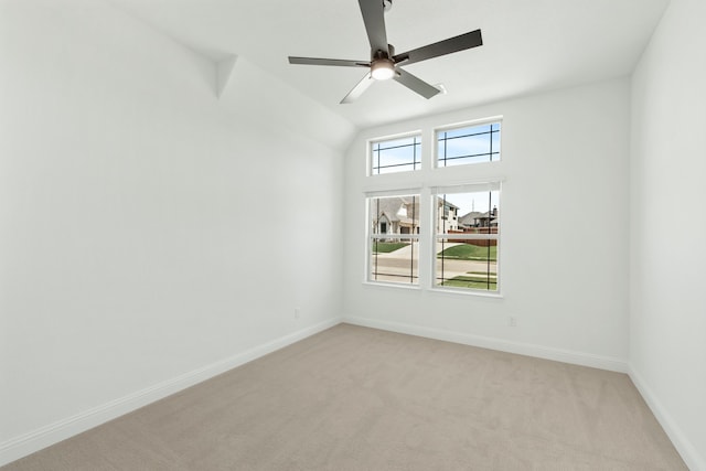 spare room with light carpet, vaulted ceiling, and ceiling fan