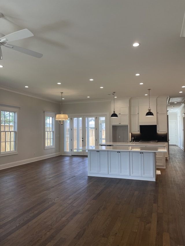 kitchen with crown molding, open floor plan, a large island, dark wood-style floors, and white cabinets