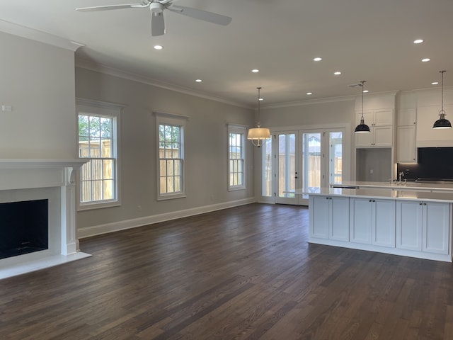 kitchen with dark wood finished floors, light countertops, white cabinets, crown molding, and open floor plan