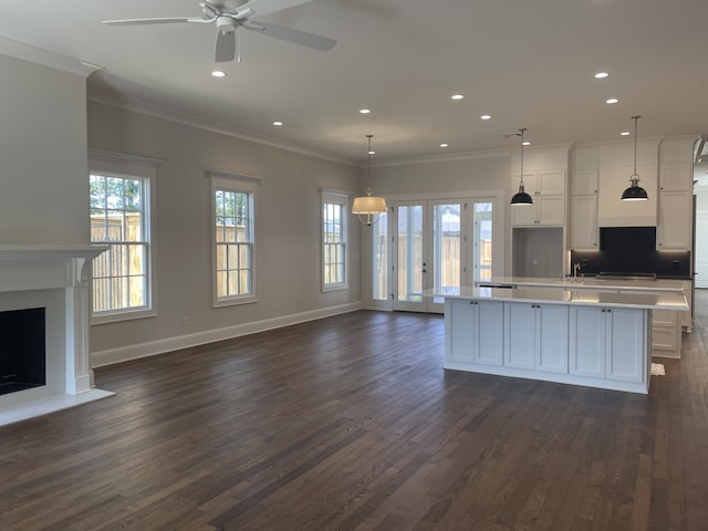 kitchen with a fireplace with raised hearth, open floor plan, light countertops, dark wood-style floors, and white cabinetry