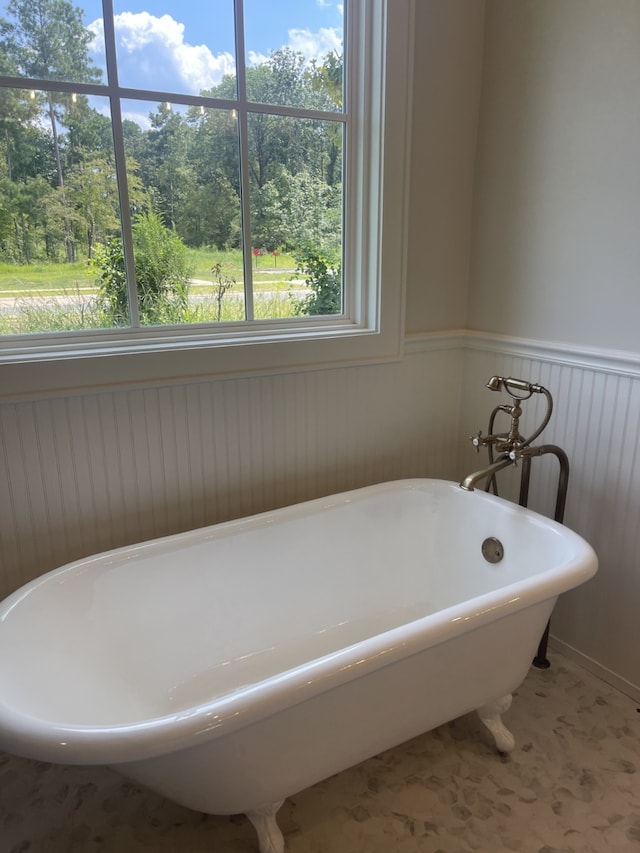 full bathroom with a soaking tub and a wainscoted wall