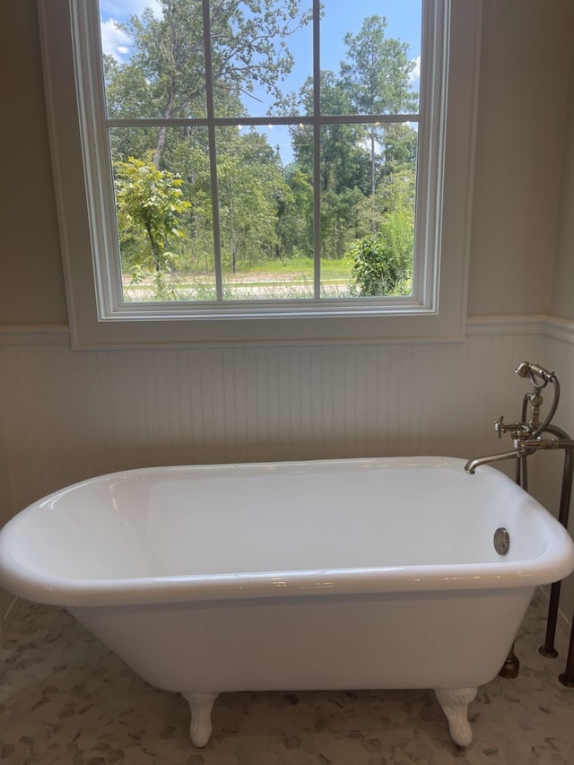 full bath with a soaking tub and a wainscoted wall