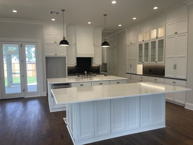 kitchen featuring visible vents, white cabinetry, a spacious island, and custom range hood