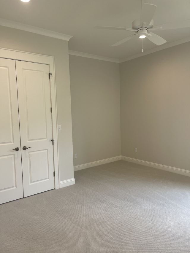 spare room with crown molding, a ceiling fan, baseboards, and light carpet