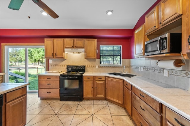 kitchen with light tile flooring, black appliances, backsplash, sink, and ceiling fan