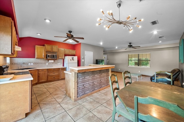 kitchen featuring white fridge, a kitchen island, backsplash, ceiling fan with notable chandelier, and sink