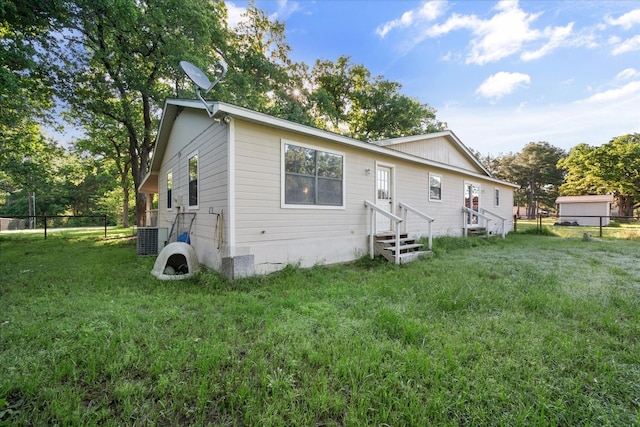 back of house with central AC and a lawn