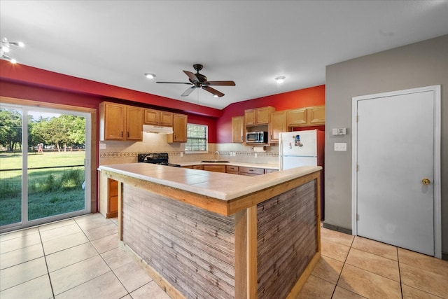 kitchen featuring backsplash, light tile floors, white fridge, and range