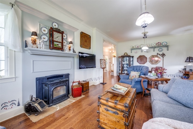 living room with hardwood / wood-style floors, ornamental molding, and a wood stove