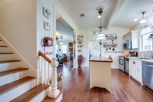 kitchen featuring appliances with stainless steel finishes, beam ceiling, dark wood-type flooring, white cabinetry, and pendant lighting