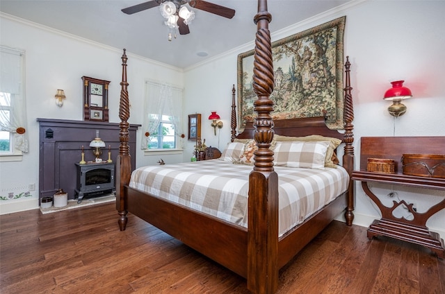 bedroom with ceiling fan, hardwood / wood-style floors, ornamental molding, and a wood stove