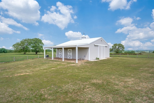 rear view of house featuring a rural view, a yard, and an outdoor structure