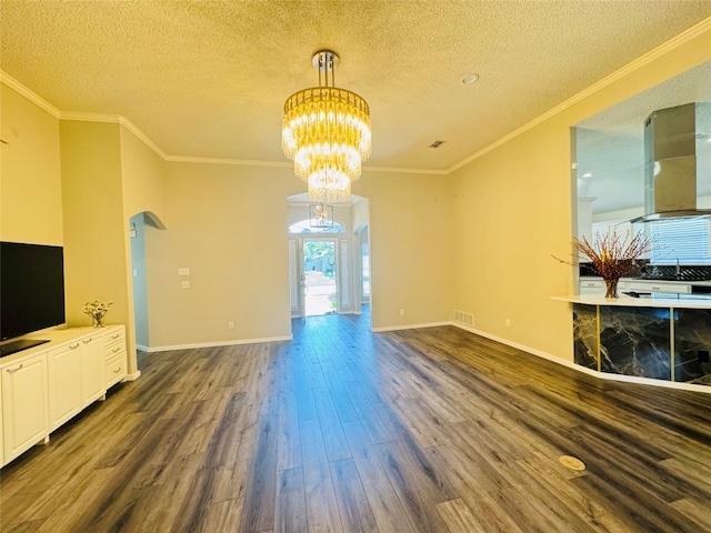 unfurnished living room featuring ornamental molding, dark wood-type flooring, a textured ceiling, and a chandelier