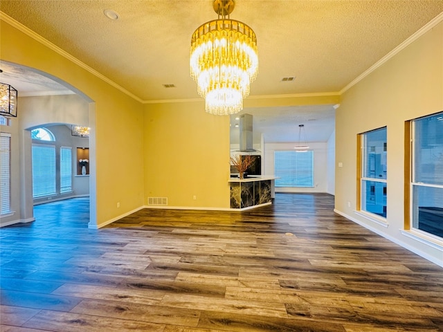 unfurnished living room featuring dark hardwood / wood-style floors, crown molding, an inviting chandelier, and a textured ceiling