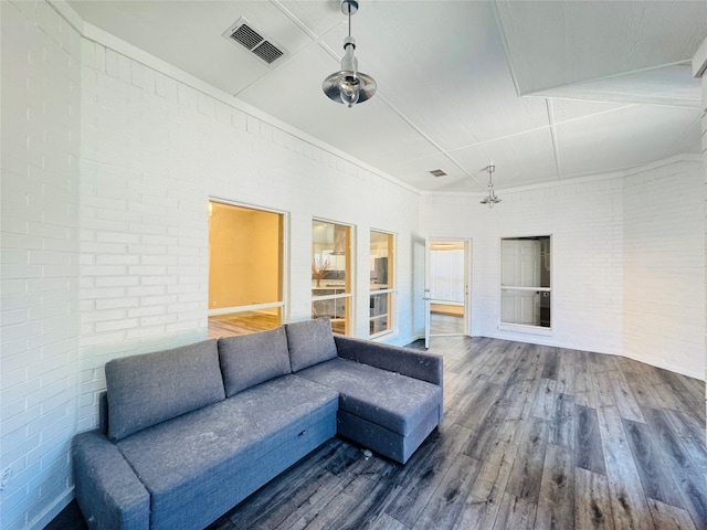 living room featuring ceiling fan, dark hardwood / wood-style flooring, and brick wall