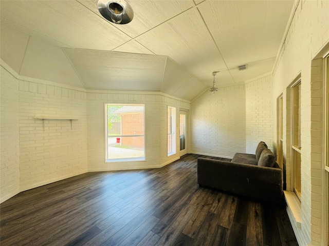 living room with ornamental molding, lofted ceiling, brick wall, and dark hardwood / wood-style floors