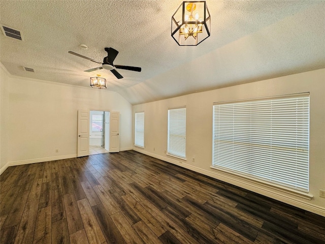 spare room featuring ceiling fan with notable chandelier, lofted ceiling, dark hardwood / wood-style flooring, and a textured ceiling