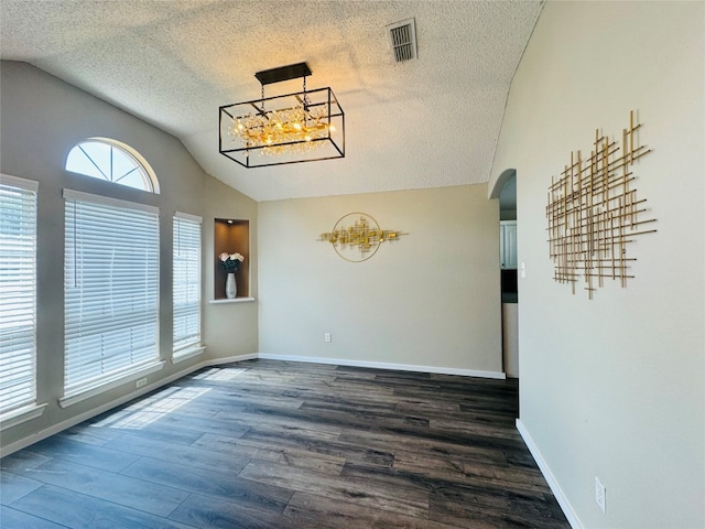 unfurnished room with an inviting chandelier, vaulted ceiling, dark hardwood / wood-style flooring, and a textured ceiling