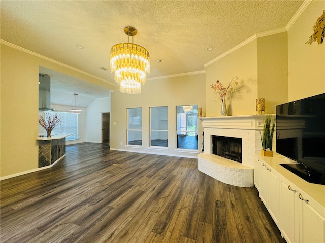 unfurnished living room featuring dark hardwood / wood-style floors, a textured ceiling, a fireplace, a notable chandelier, and ornamental molding