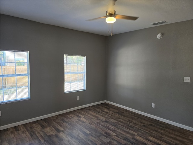 unfurnished room featuring plenty of natural light, dark wood-type flooring, and ceiling fan