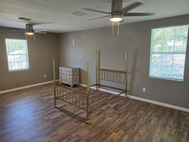 living area featuring a healthy amount of sunlight, dark hardwood / wood-style flooring, and ceiling fan