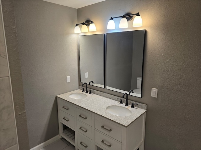 bathroom with toilet and dual vanity