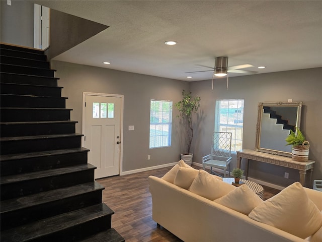 living room with a wealth of natural light, dark wood-type flooring, and ceiling fan